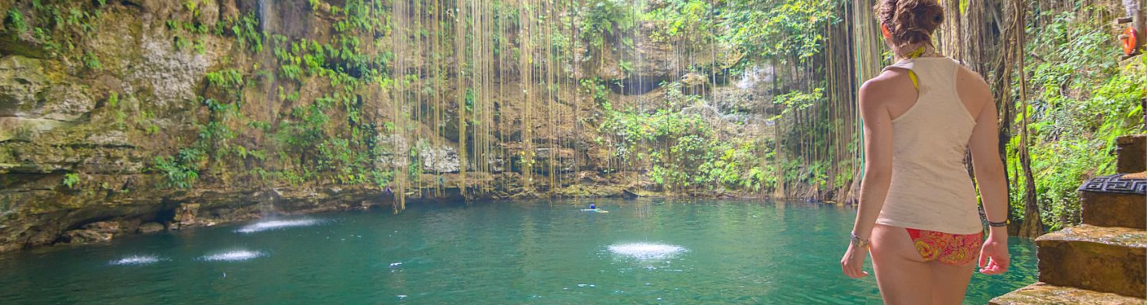 Back view of woman in swimwear overlooking blue swimming lagoon with tropical vegetation