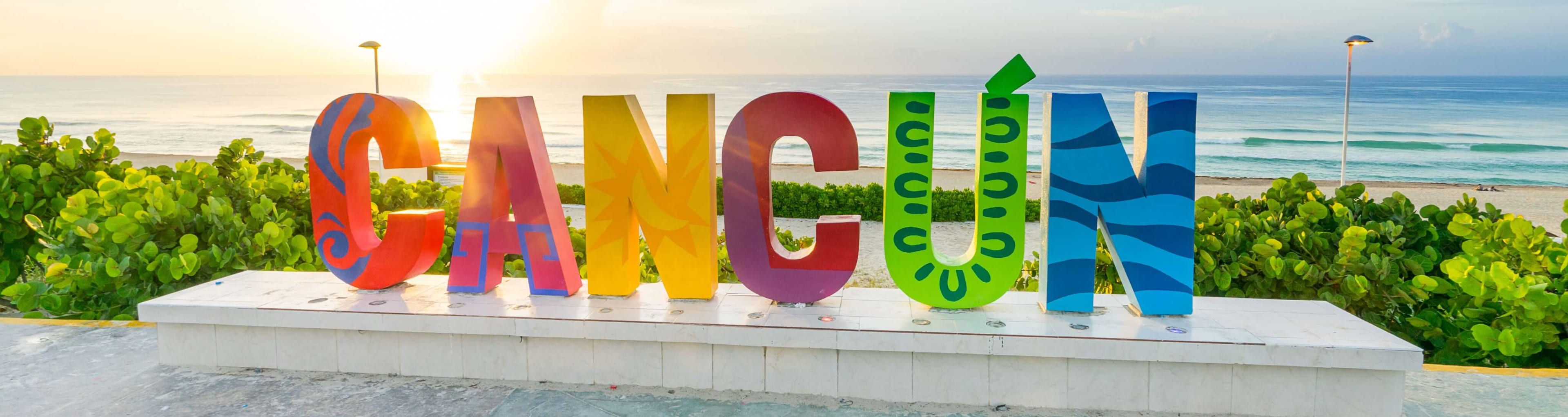 A colorful Cancun sign standing by the ocean