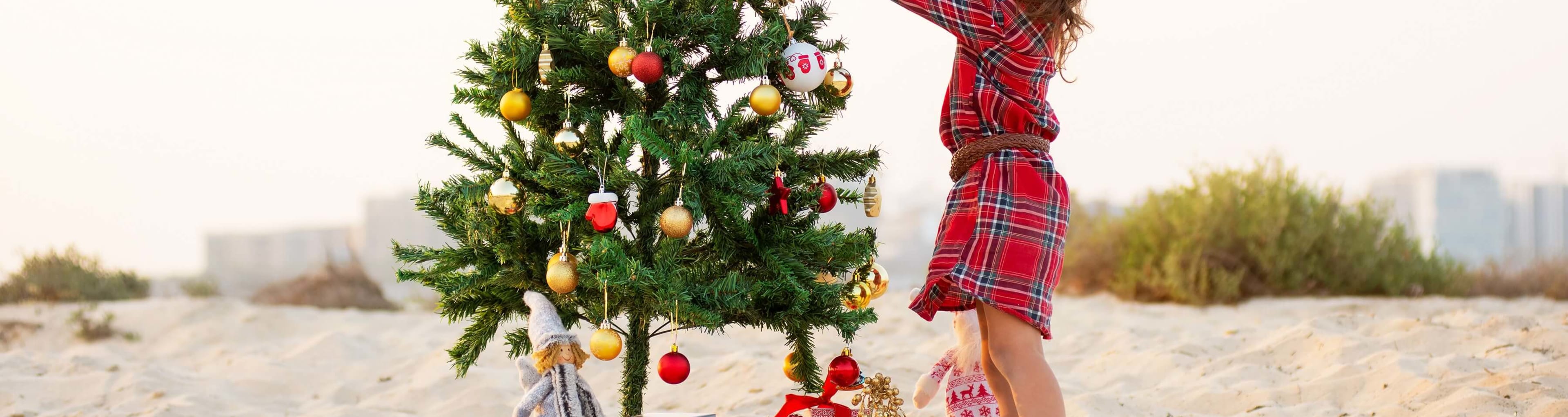 A child decorates a Christmas tree on the beach