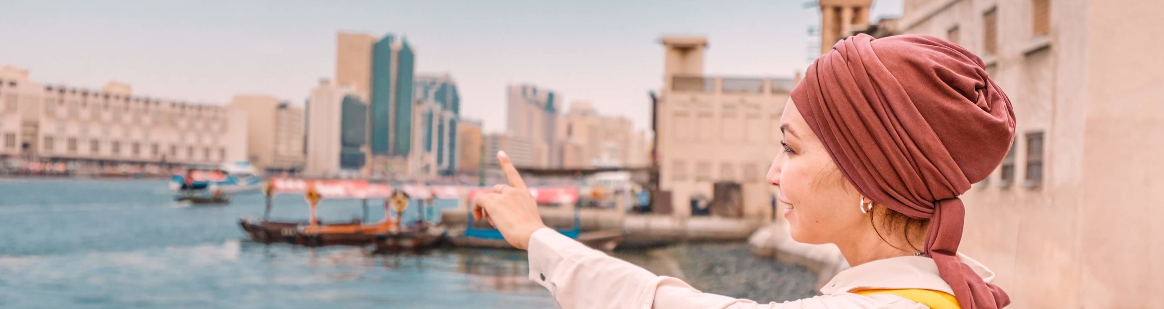 A woman points to the opposite side of Dubai Creek