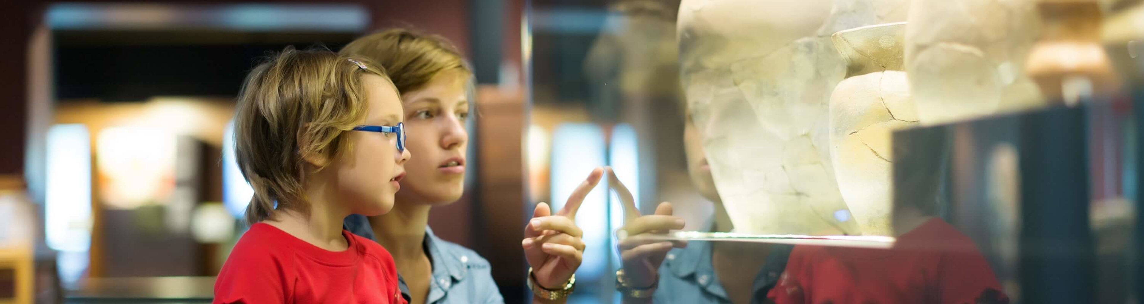 A mother and child explore a museum