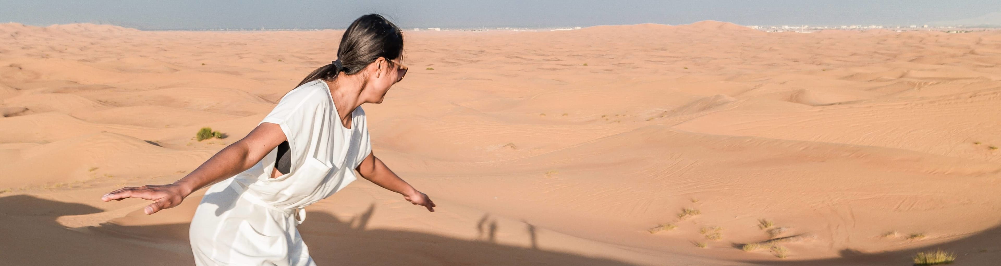A woman tries sandboarding down a Dubai desert dune