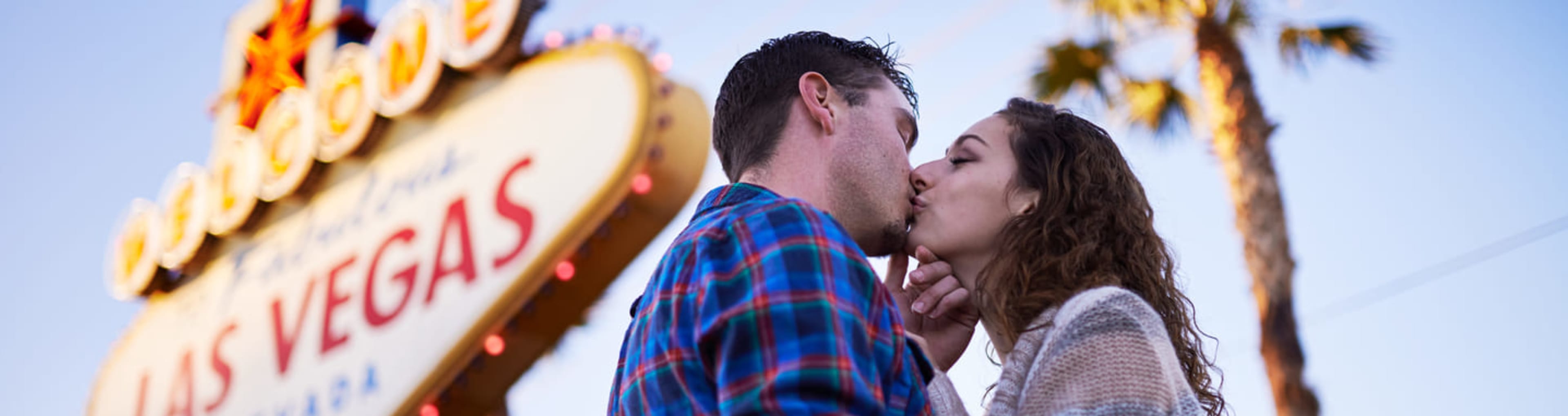 Young couple kissing by the 'Welcome to Fabulous Las Vegas' sign