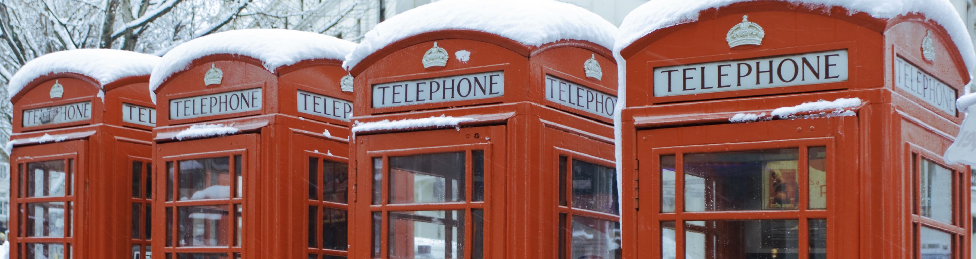 A row of red telephone boxes covered in snow