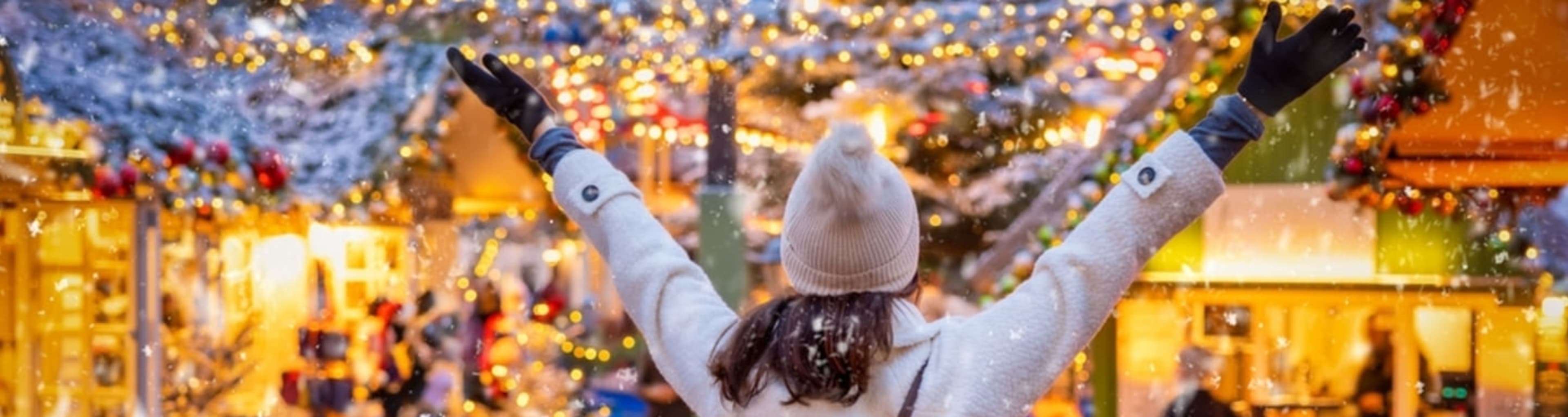 Woman raising her arms in joy at a Christmas market.