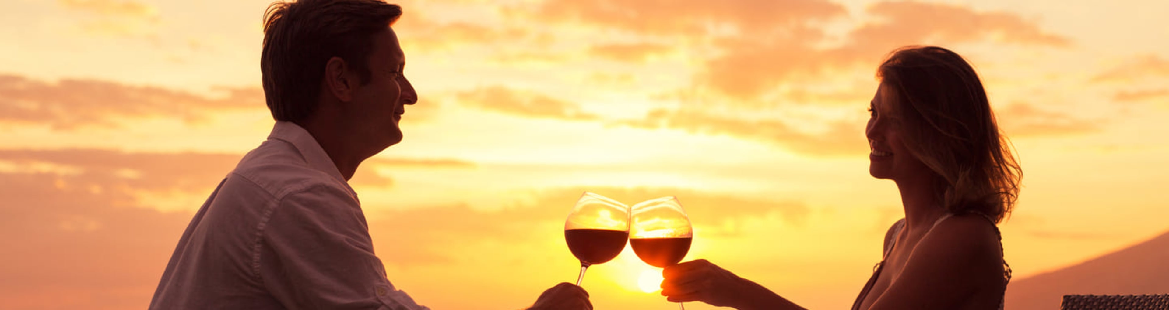 Couple drinking wine on a beach at sunset
