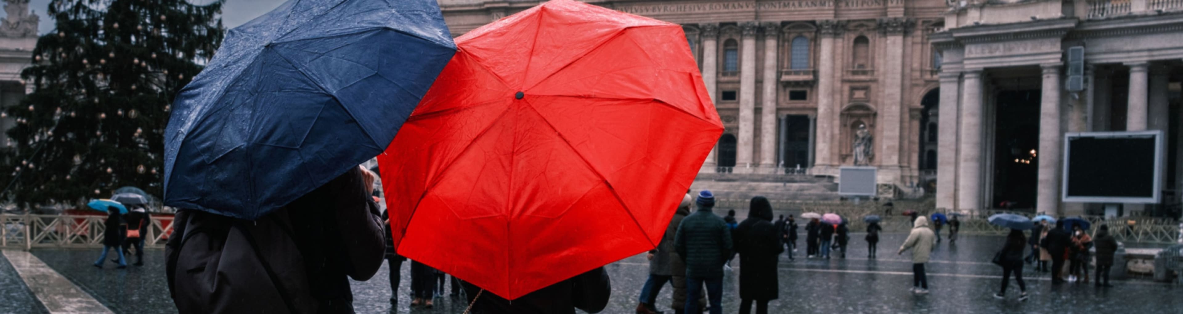 Couple with umbrellas in front of St Peter's Basilica in Rome