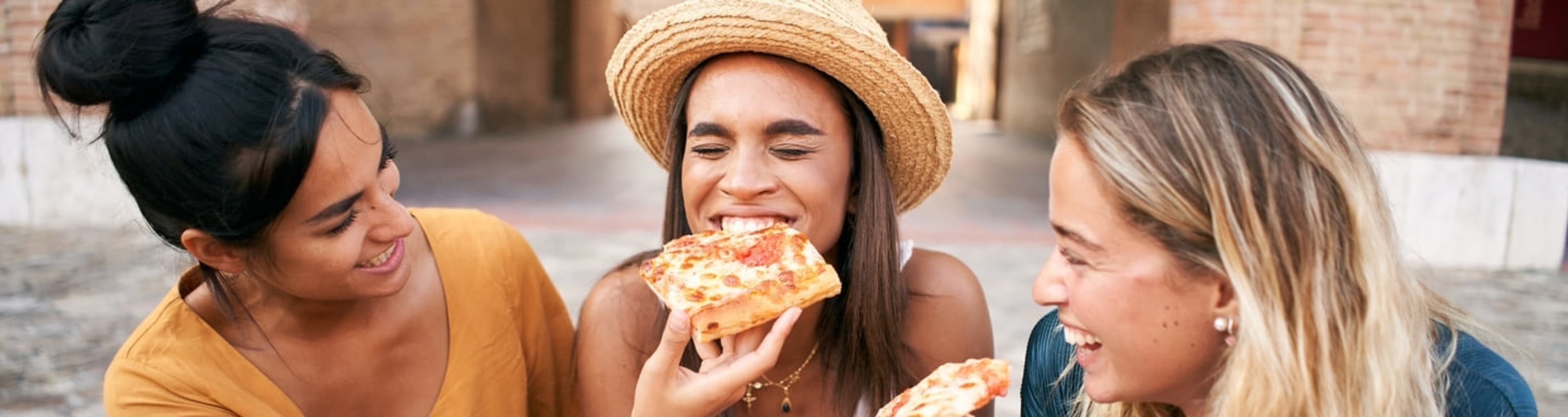 Women laughing and eating pizza in Rome