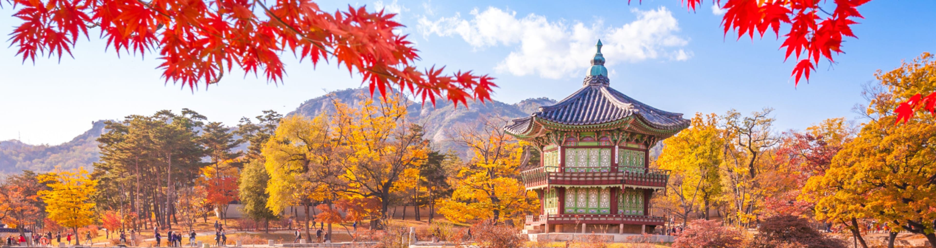 A pond with a Korean pavilion and red autumn leaves