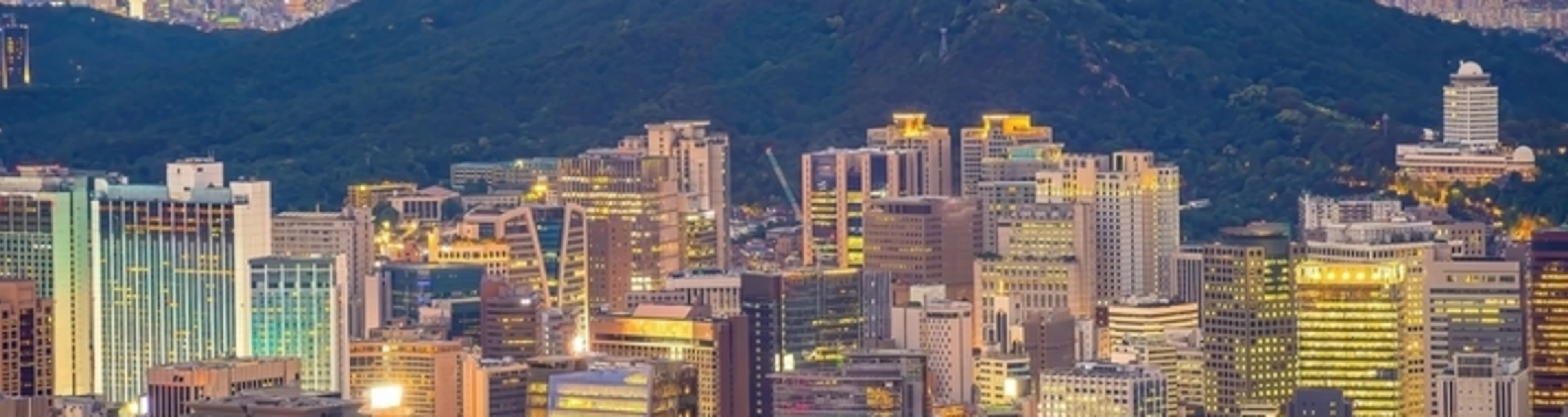 The Seoul skyline at sunset, dominated by Namsan Mountain and the N Seoul Tower.