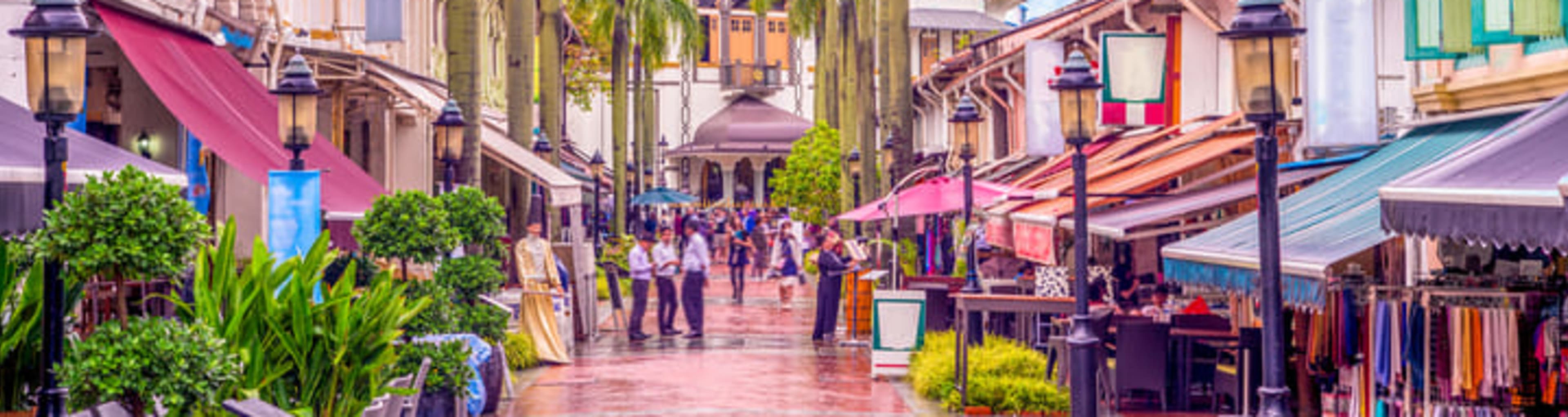 The colorful Kampong Glam district in Singapore, with the golden dome of the Sultan Mosque visible behind the palm trees.