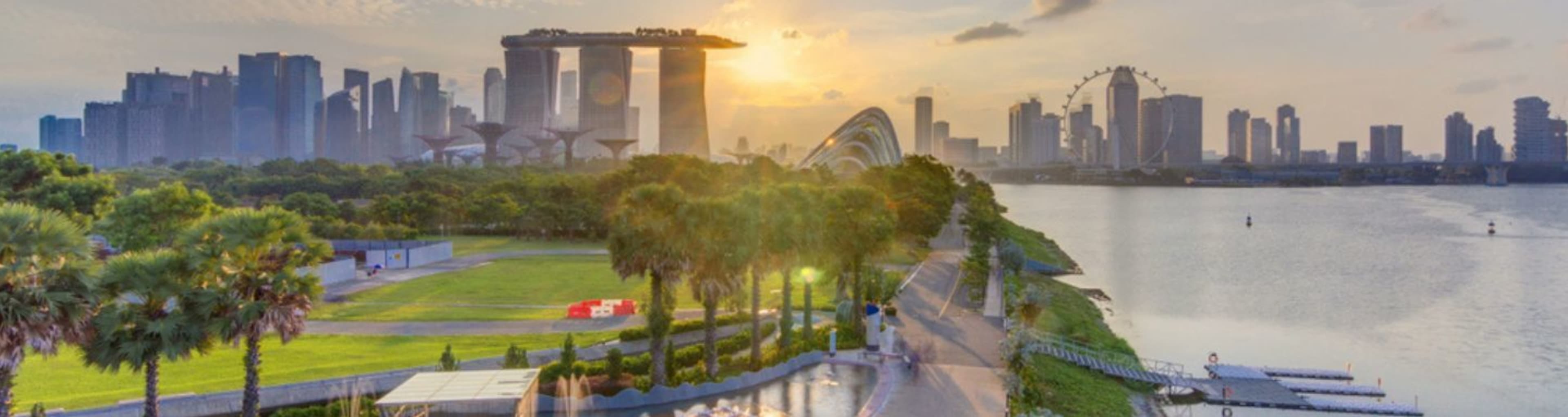 Panorama of the Singapore skyline as sun rises with green space, the river and Marina Bay Sands