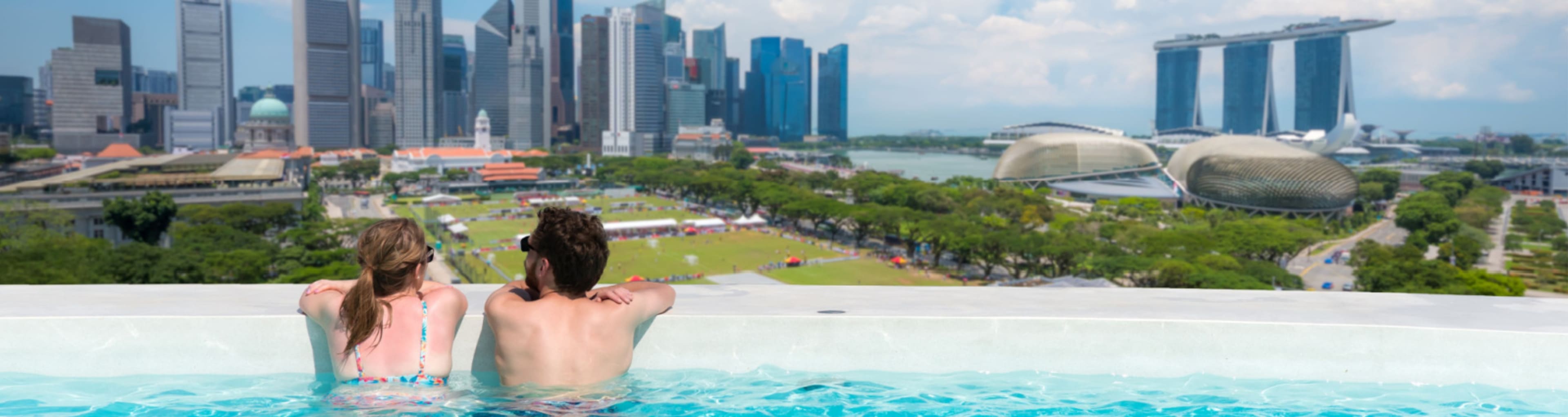 Couple look from a rooftop pool over Singapore Marina