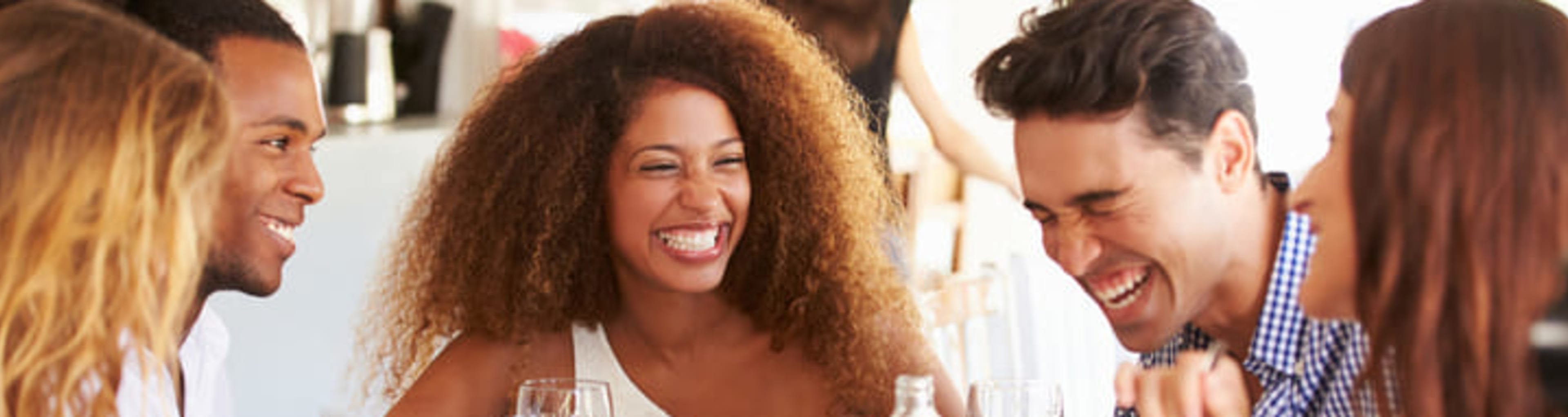 Group of friends chatting and laughing over a meal in a restaurant.