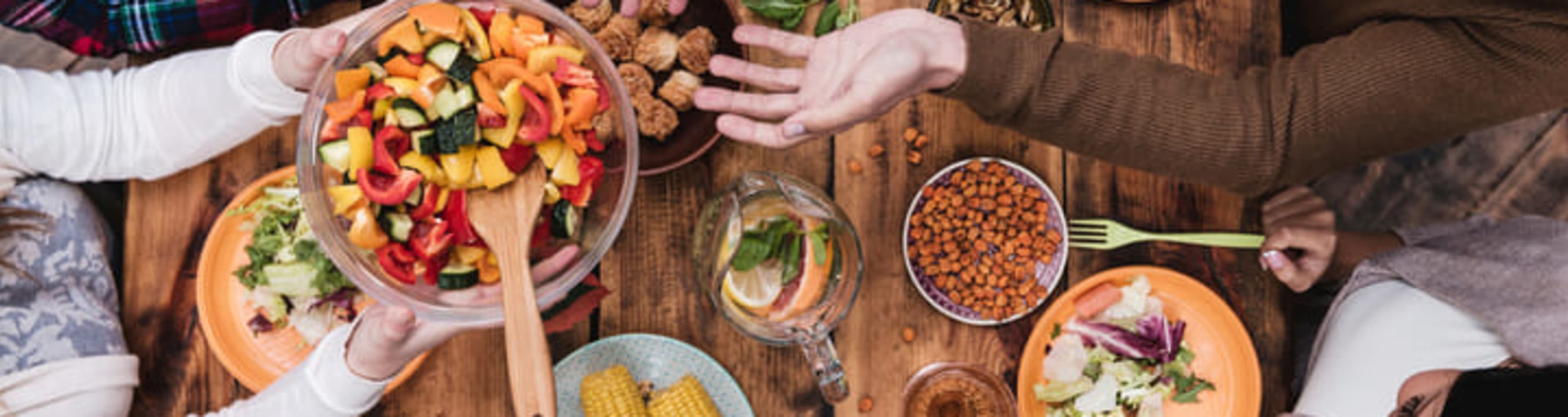 Friends sharing vegetarian food across a large communal table.