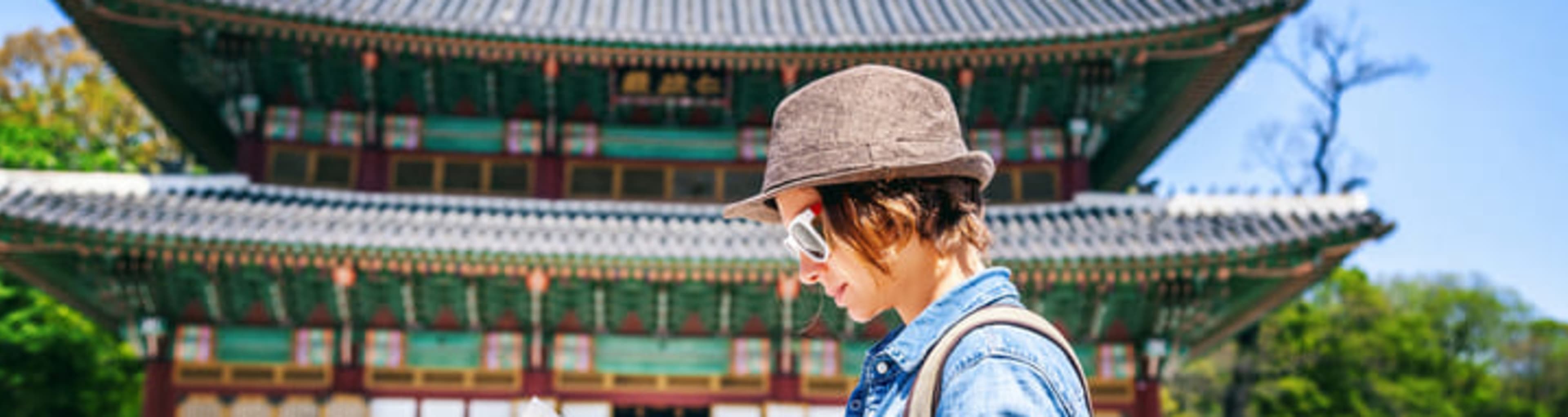 Woman studying a map in front of a pagoda-style building in Seoul.