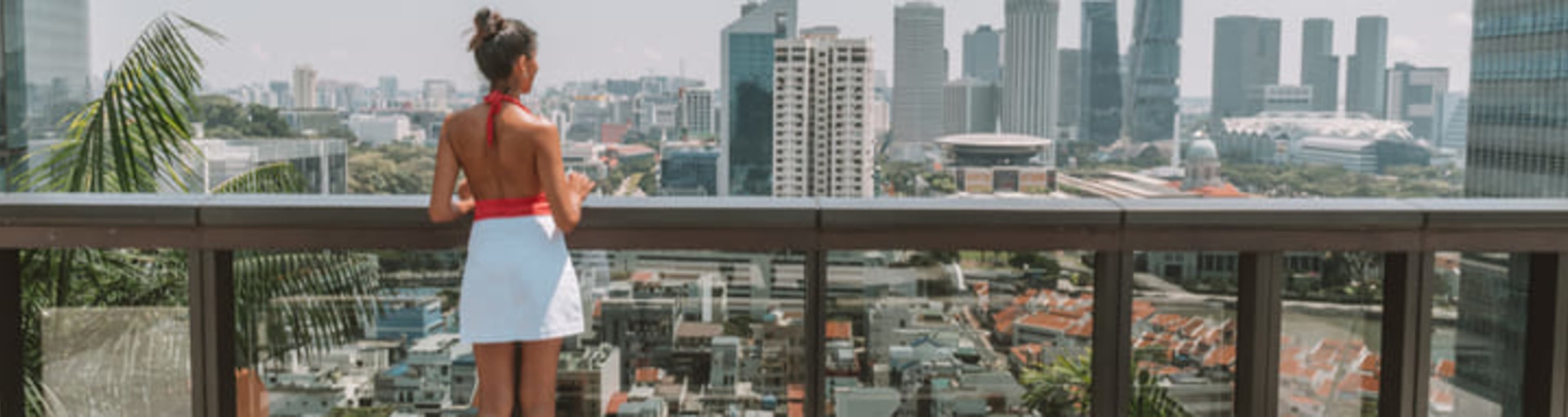 Woman gazing at the Singapore skyline from a hotel balcony