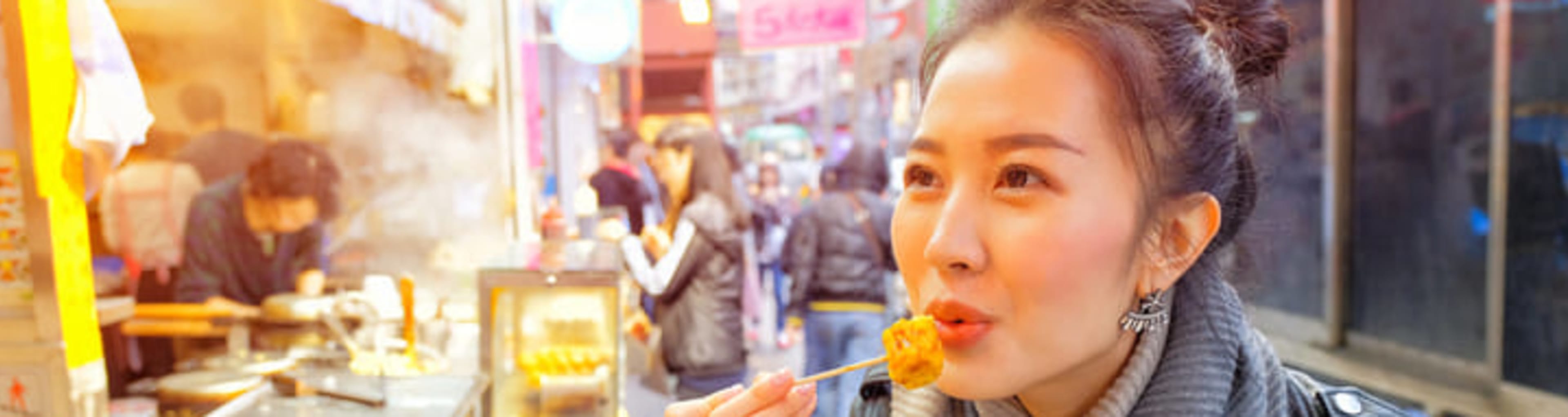 Woman eating freshly cooked takeaway dumplings inside a hawker center.