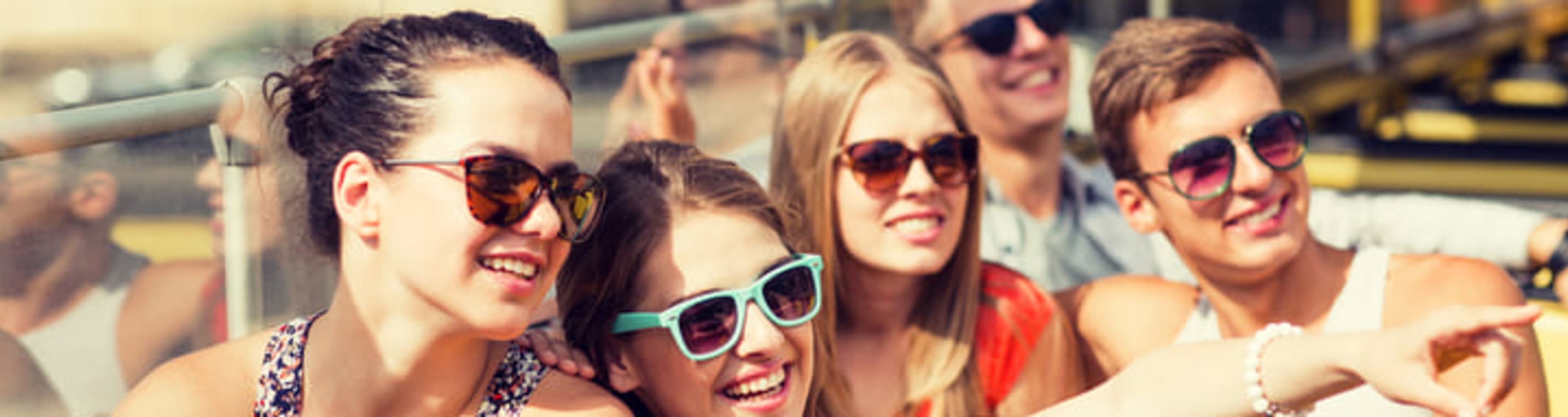 Family with teenage kids riding an open-top bus in the sunshine