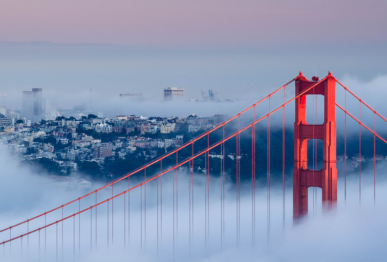 Tip of the Golden Gate Bridge peaking out above a cloud of fog