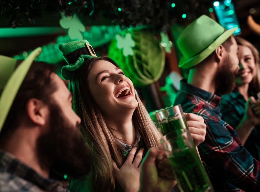 People celebrating St. Patrick's Day, wearing green leprechaun hats and laughing