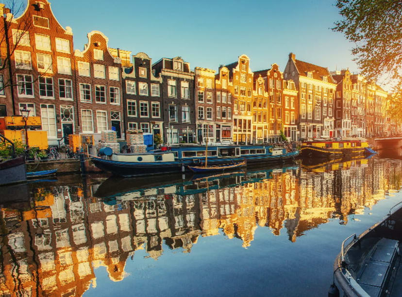 Several boats moored beside Amsterdam's iconic canal houses