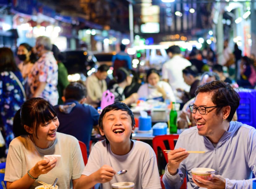 Family eating street food together in Bangkok's Chinatown.