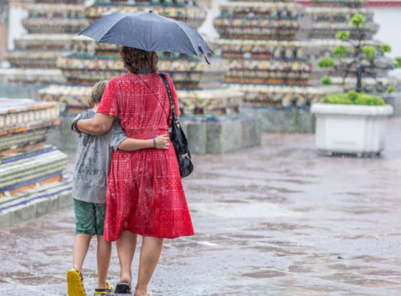 Woman and child walking in the rain under an umbrella in Bangkok.