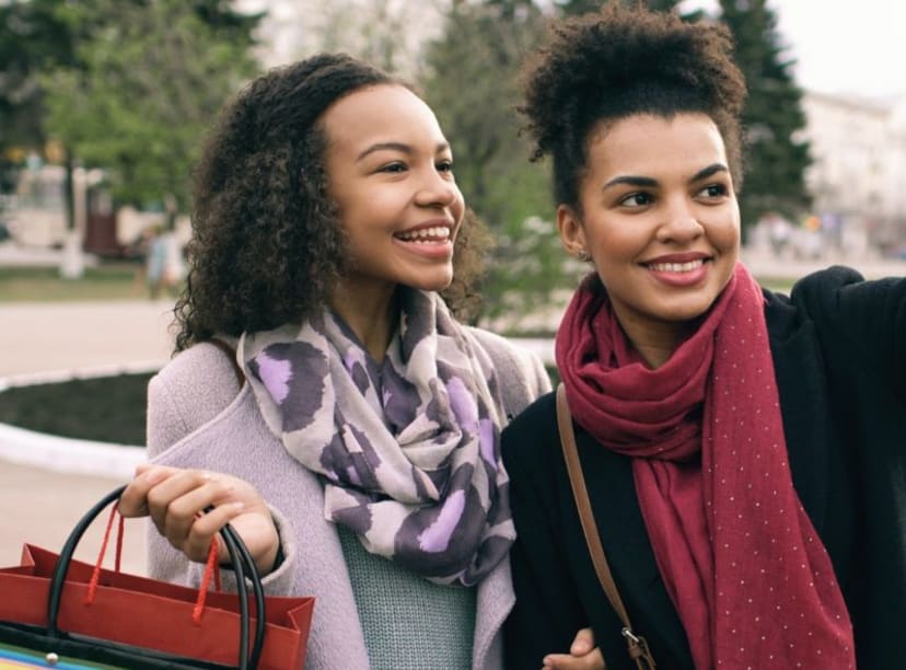 Two women smiling for a selfie, whilst holding shopping bags