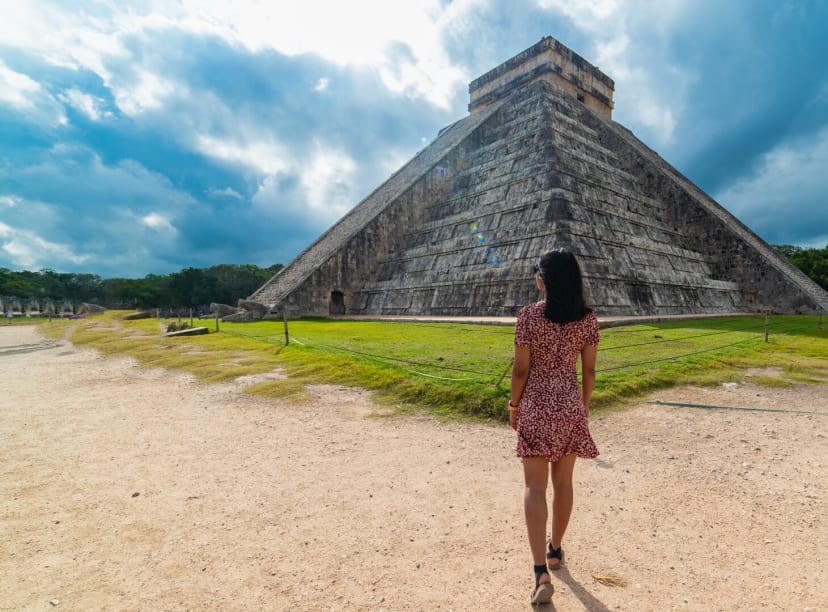 Woman walks towards the pyramid at Chichen Itza Mayan city