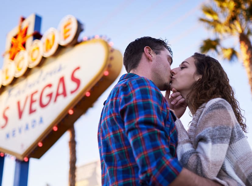 Young couple kissing by the 'Welcome to Fabulous Las vegas' sign