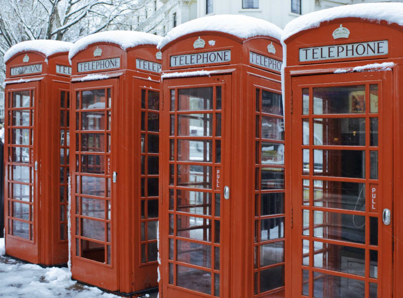 A row of red telephone boxes covered in snow