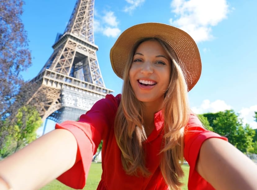 Woman taking a selfie in front of the Eiffel Tower on a summer day