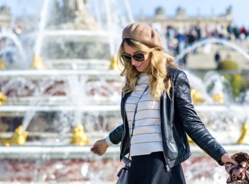 Woman walking by a fountain in the Palace of Versailles gardens.