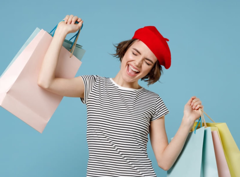 A lady in a beret and striped shirt carries several shopping bags