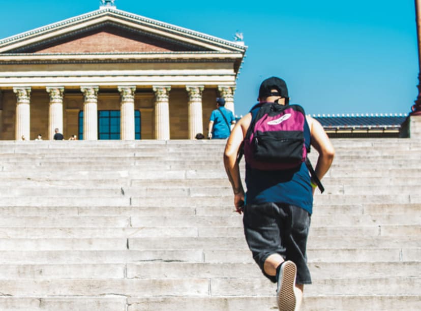 Man recreating the iconic scene from 'Rocky' on the steps of the Philadelphia Museum of Art.