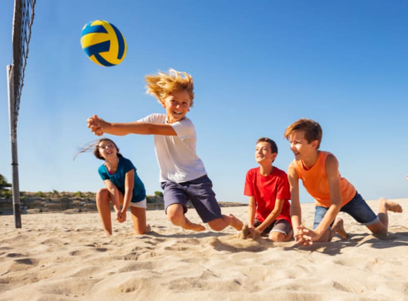A group of kids playing beach volleyball