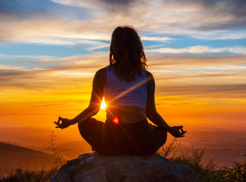 Woman meditating on a rock at sunset in San Diego