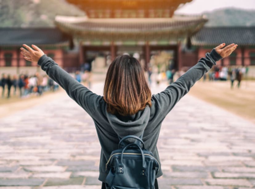 Woman raising her arms in celebration as she arrives at Gyeongbokgung Palace in Seoul.