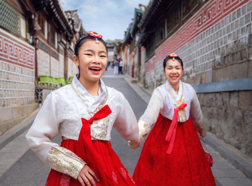 Young women in traditional hanboks having fun in a hanok village