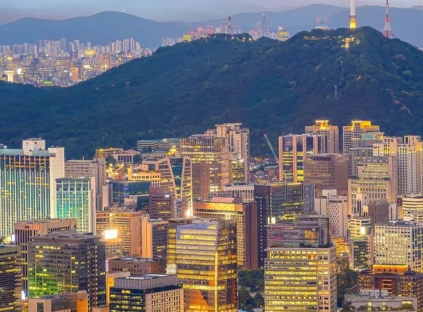 The Seoul skyline at sunset, dominated by Namsan Mountain and the N Seoul Tower.