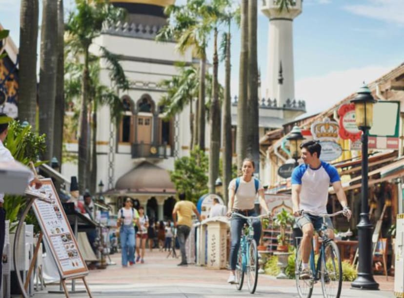 Two people cycling in front of a temple with a golden dome, Singapore