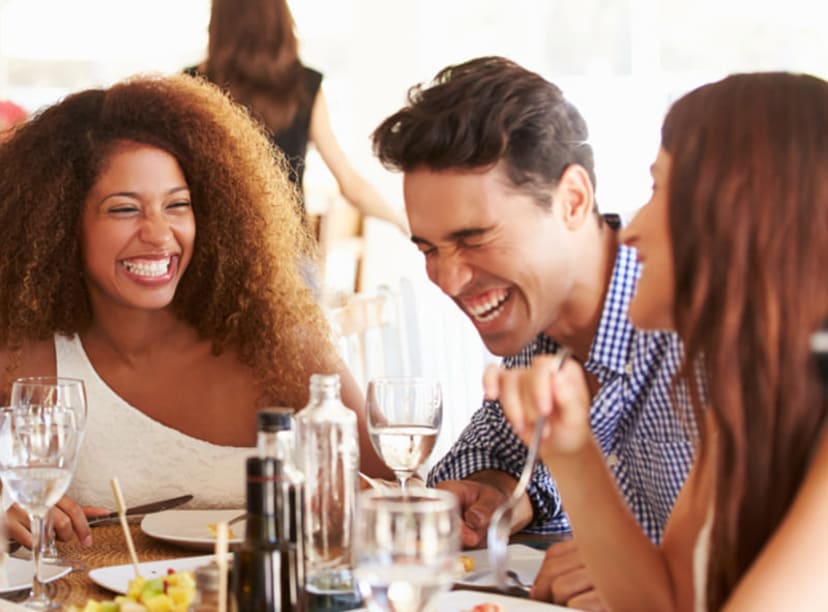 Group of friends chatting and laughing over a meal in a restaurant.