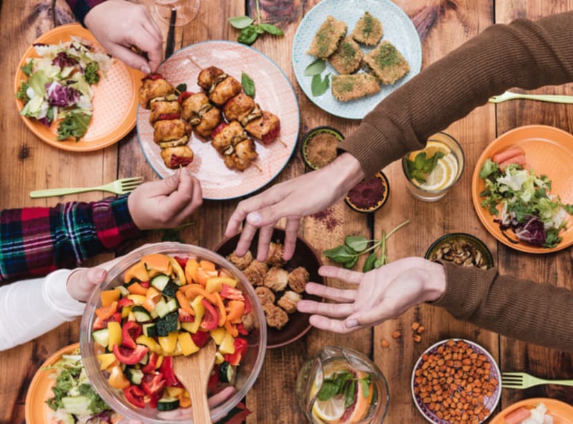 Friends sharing vegetarian food across a large communal table.