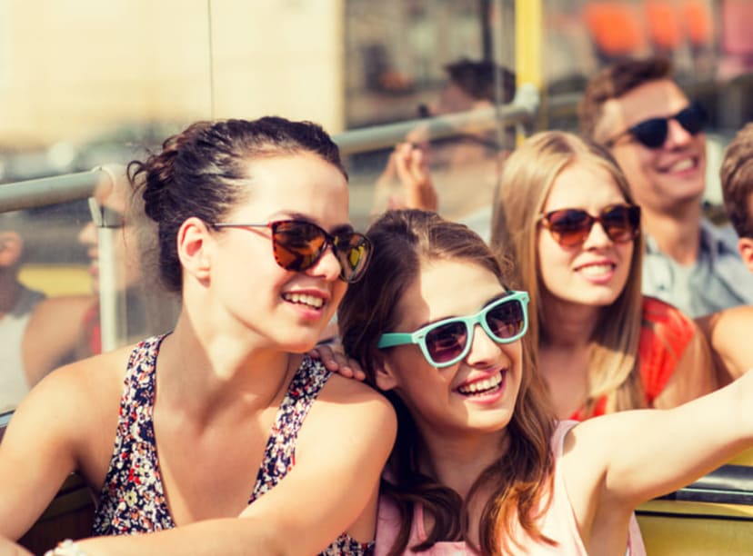 Family with teenage kids riding an open-top bus in the sunshine