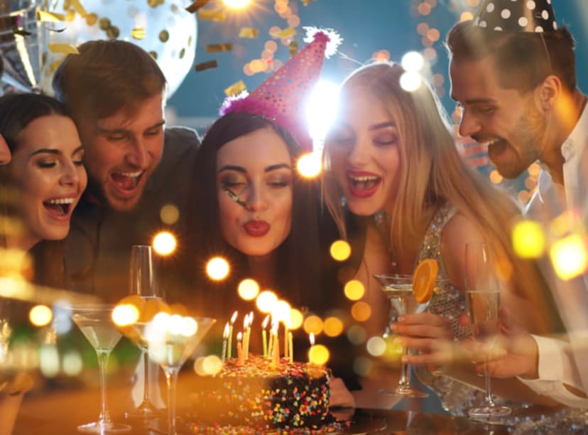 A group of friends celebrating a birthday by blowing out candles on a cake