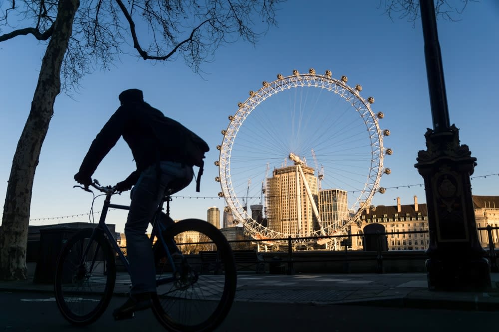Silhouette of man cycling past the London Eye