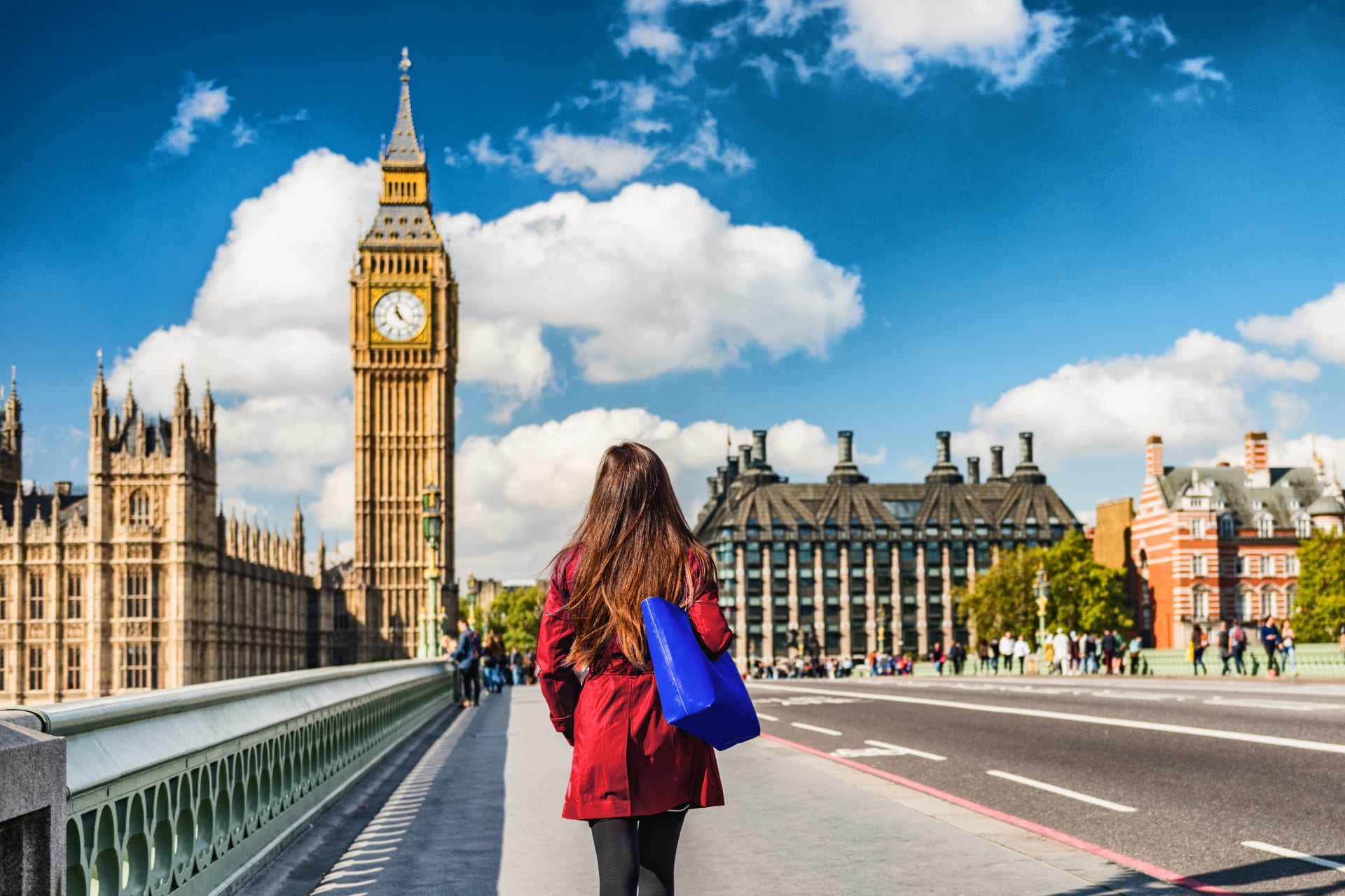 Mujer con gabardina y un gran bolso camina en dirección al Big Ben, Londres.