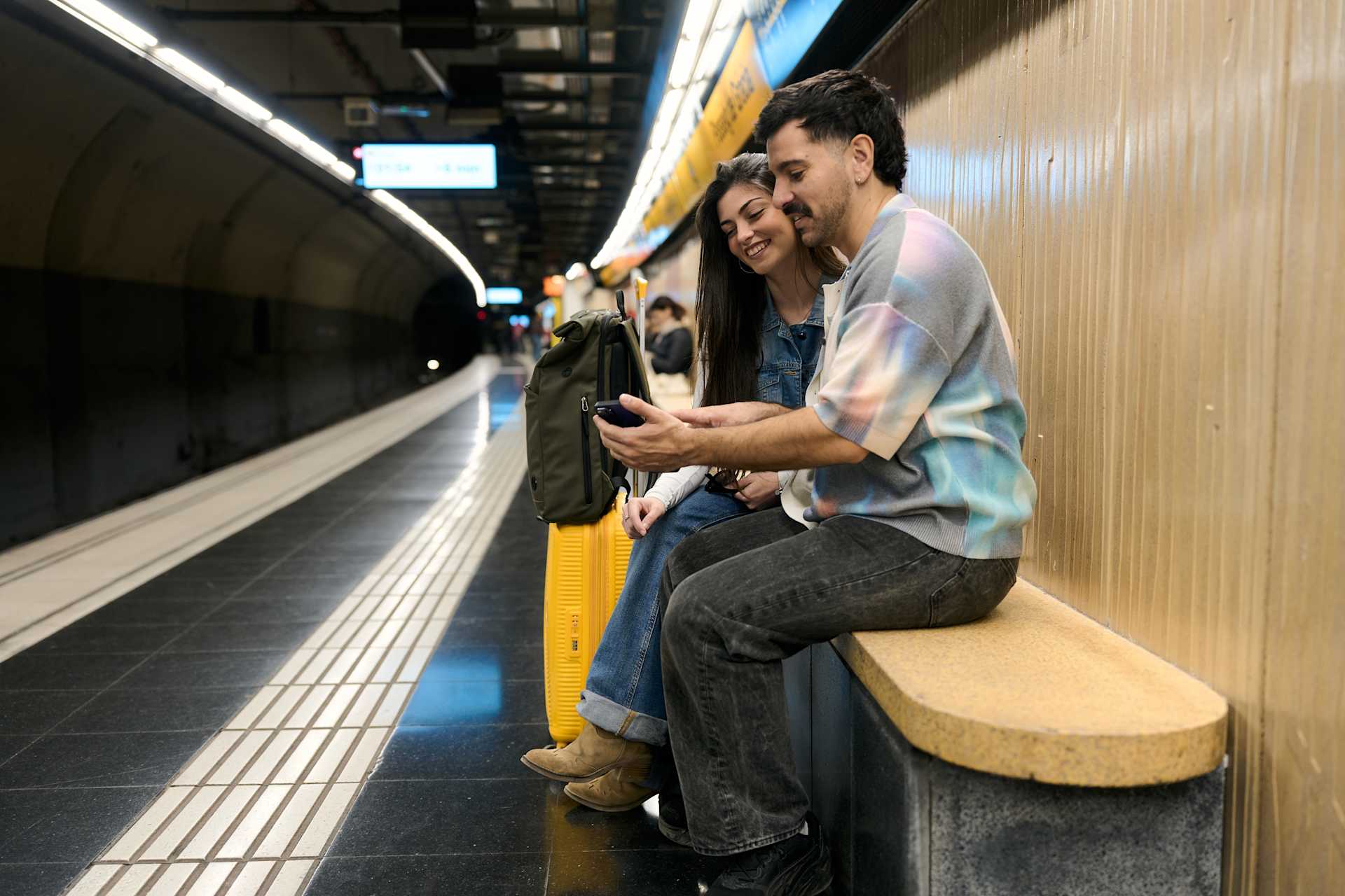 young couple waiting for a train with their luggage