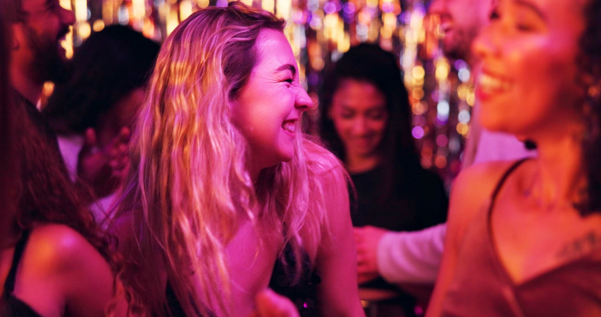 Chica baila divertida en una discoteca rodeada de gente. Planes en Cancún en invierno.